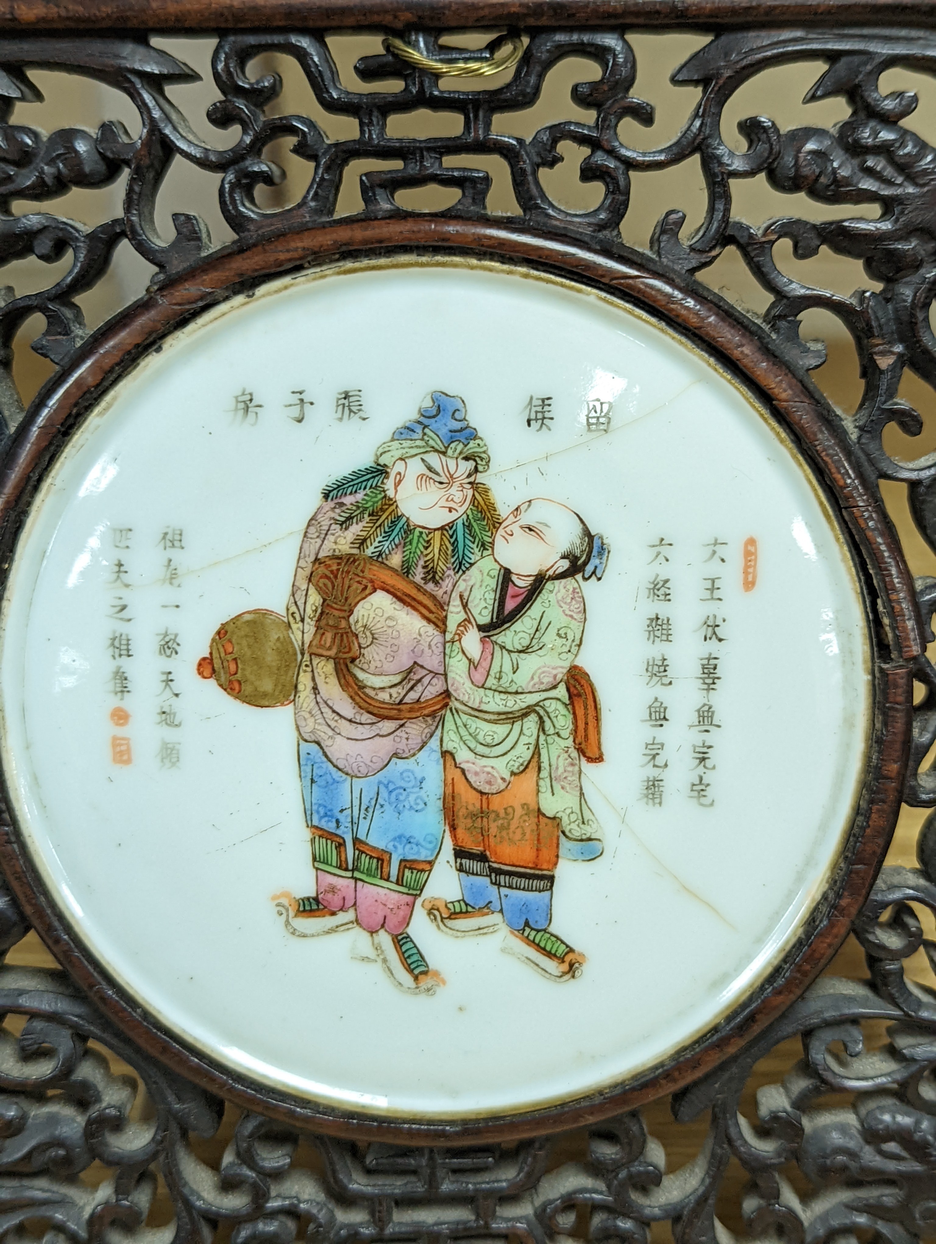 A 19th century Chinese famille rose circular plaque or cover, inset into a wood surround, cracks 15cm sq
